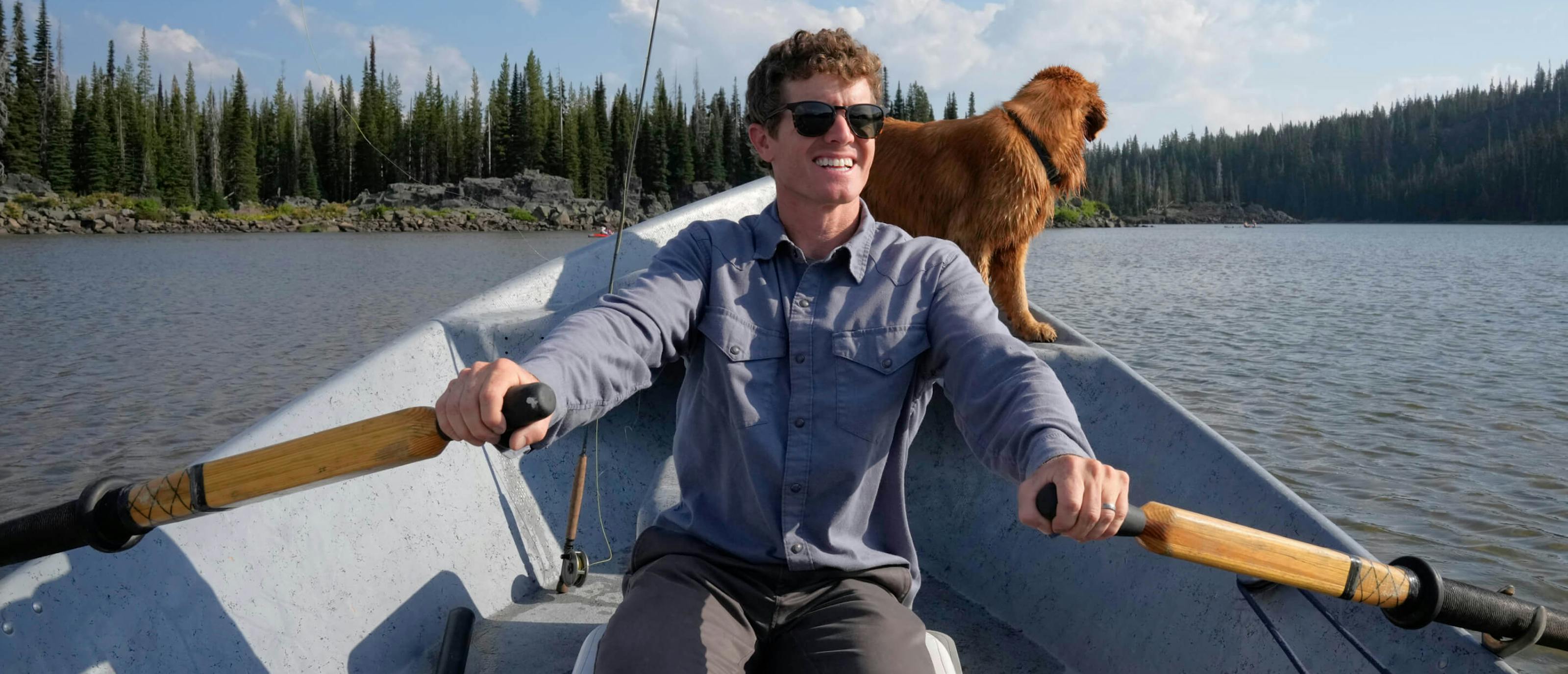 Man rowing boat with golden retriever