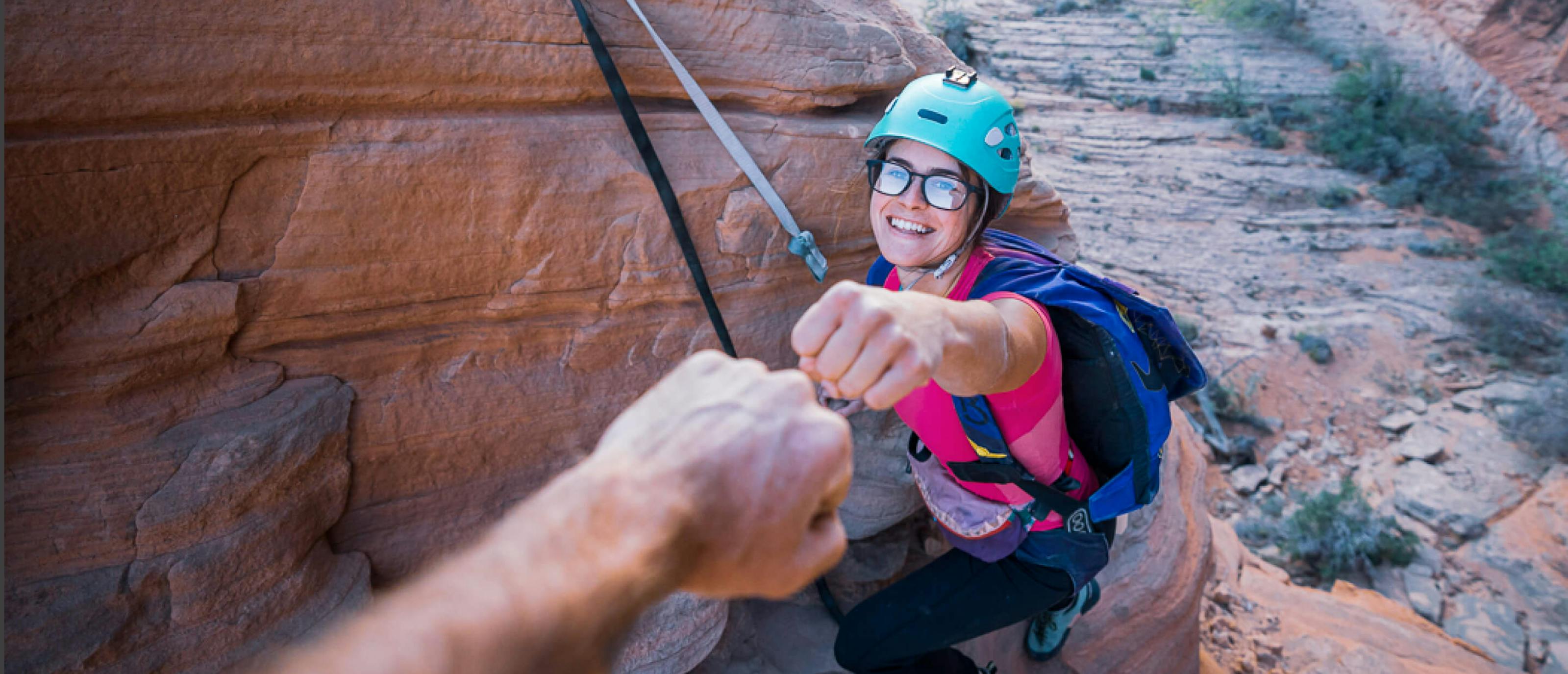 Woman in rock climbing gear giving a fist bump