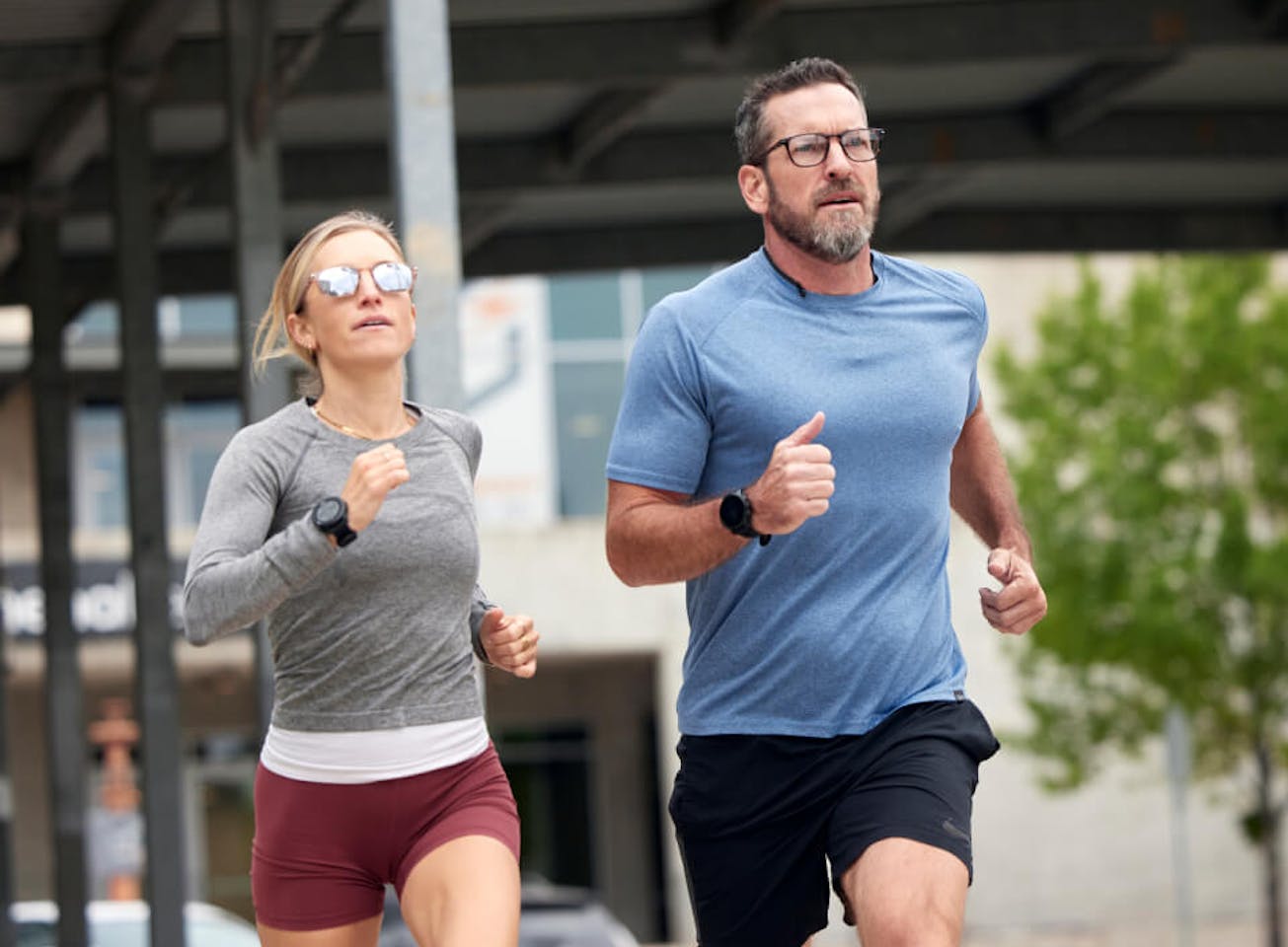 Man and woman running under bridge wearing ROKA glasses