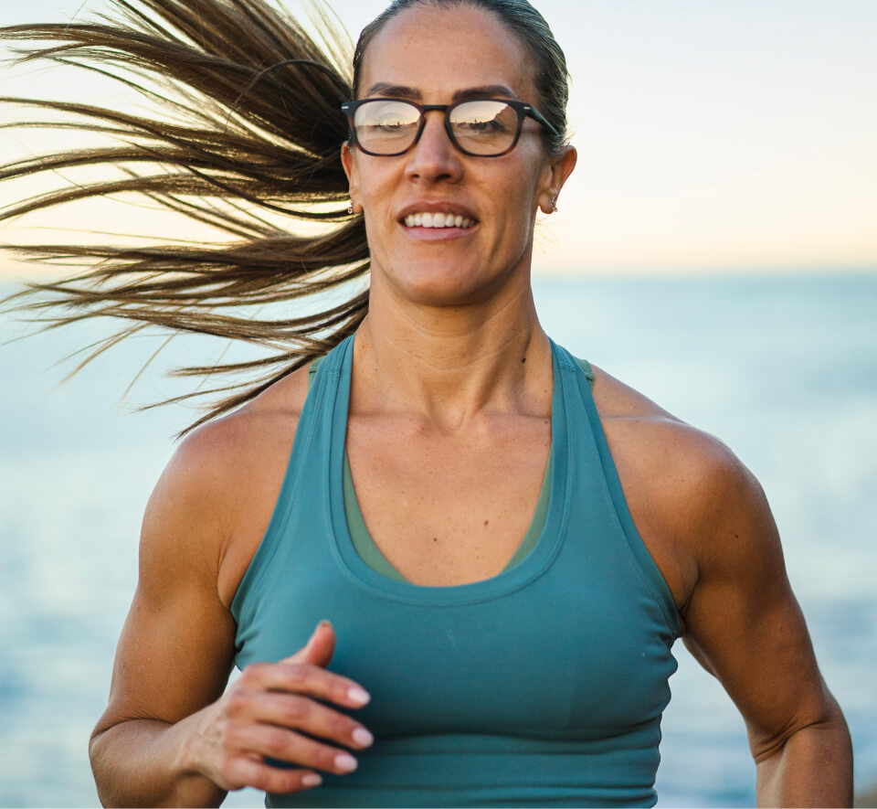 Woman jogging near ocean in blue tank top