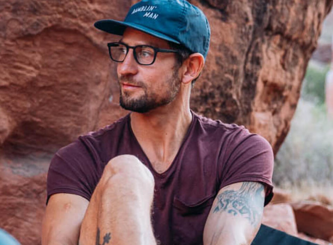 Man putting on climbing shoes in boulder area wearing ROKA glasses