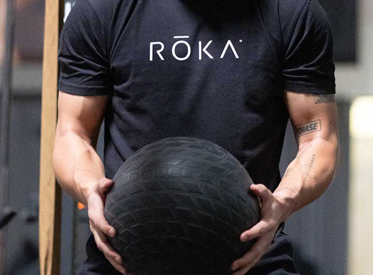Man holding medicine ball in ROKA black T-Shirt
