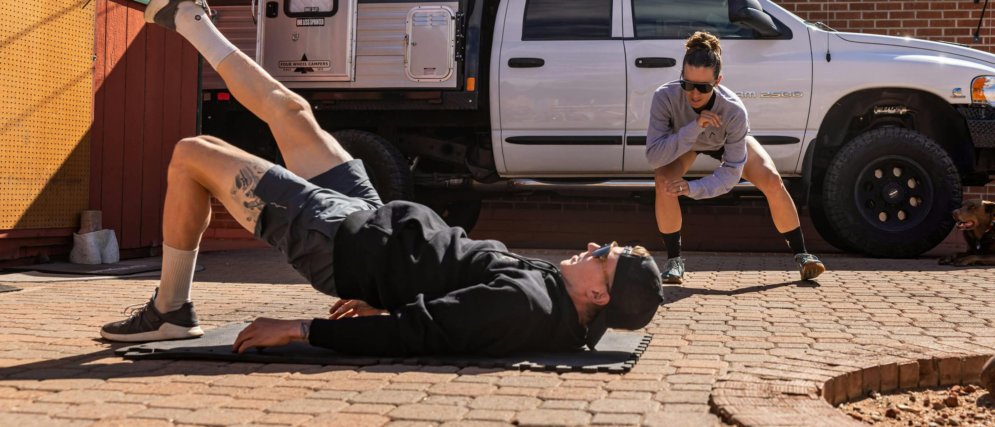 Man and woman working out next to truck in ROKA sweatshirts