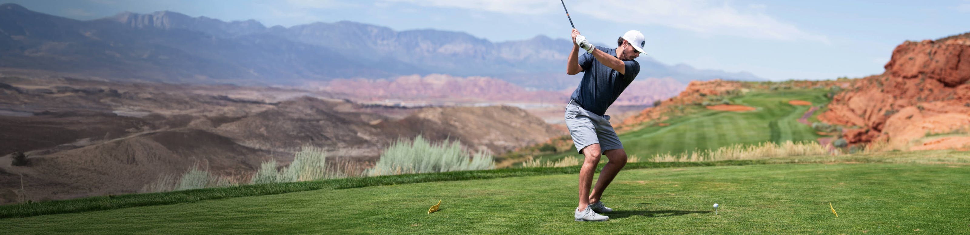 Man in white hat swinging golf club