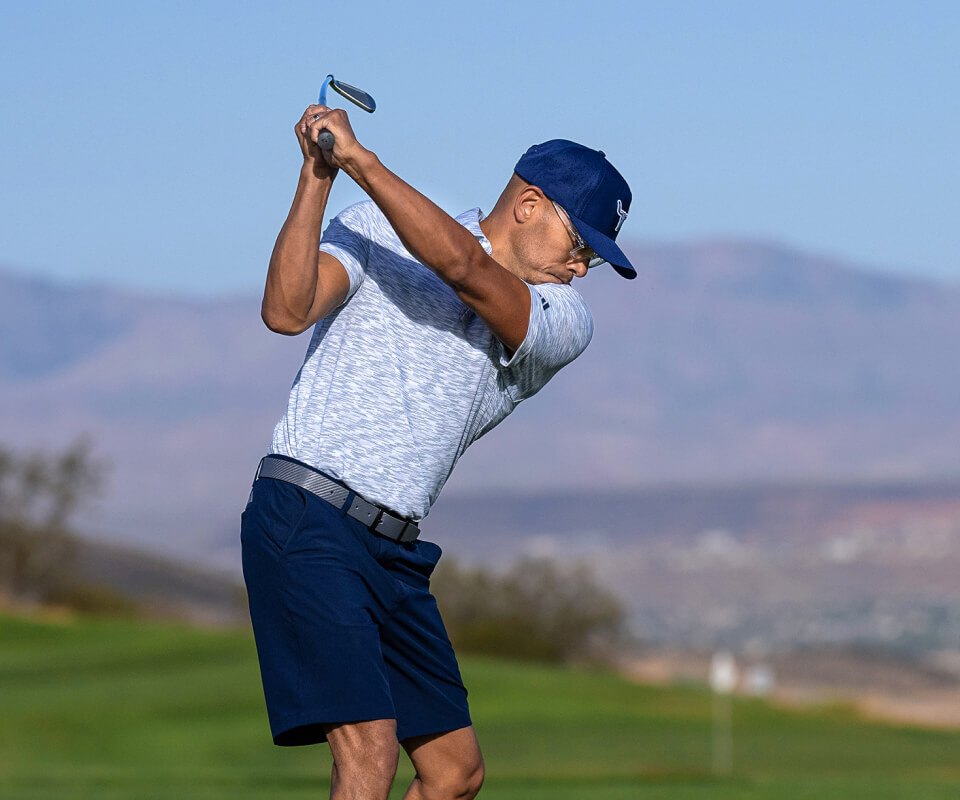 Man in blue shirt swinging golf club