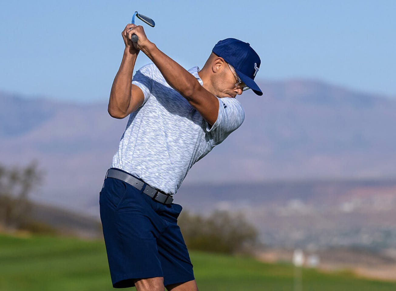 Man in blue shirt swinging golf club