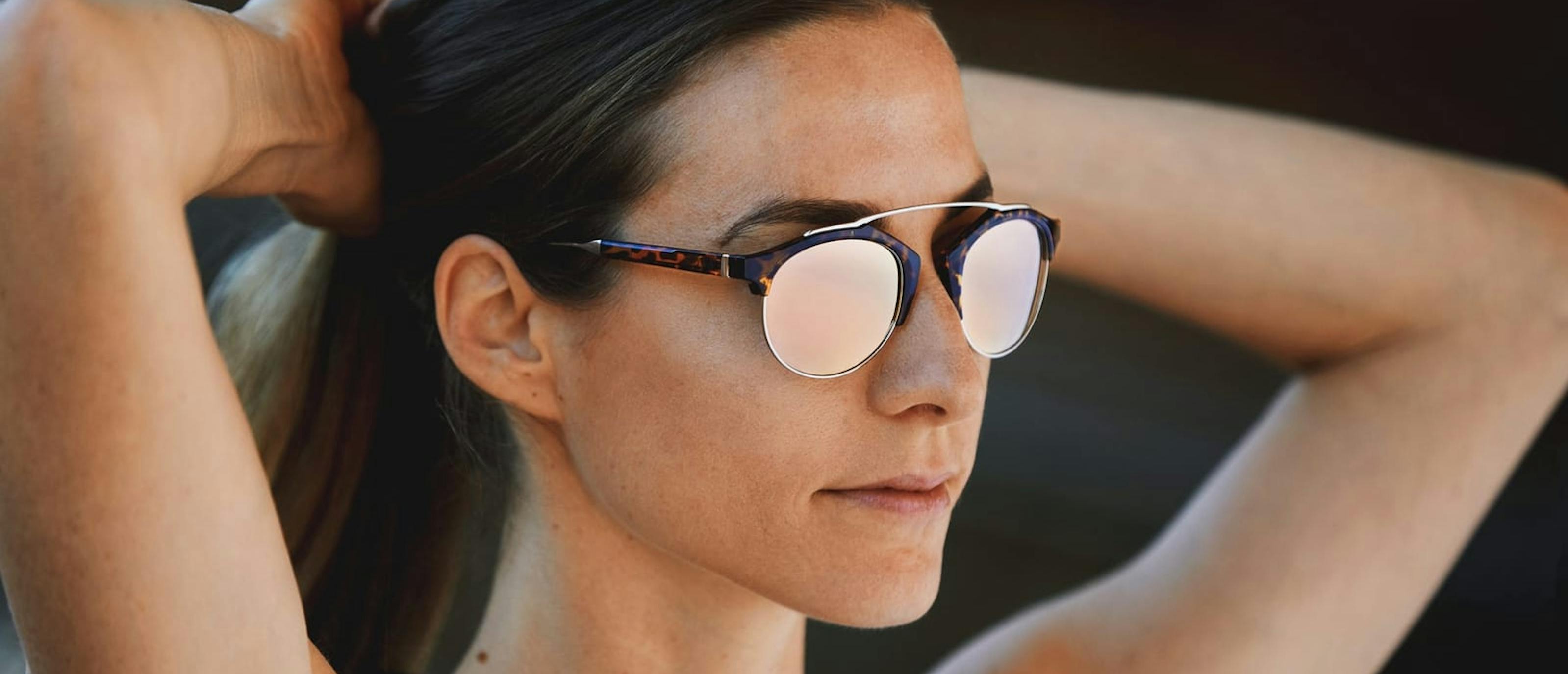 Woman tying back hair in Mallorca sunglasses
