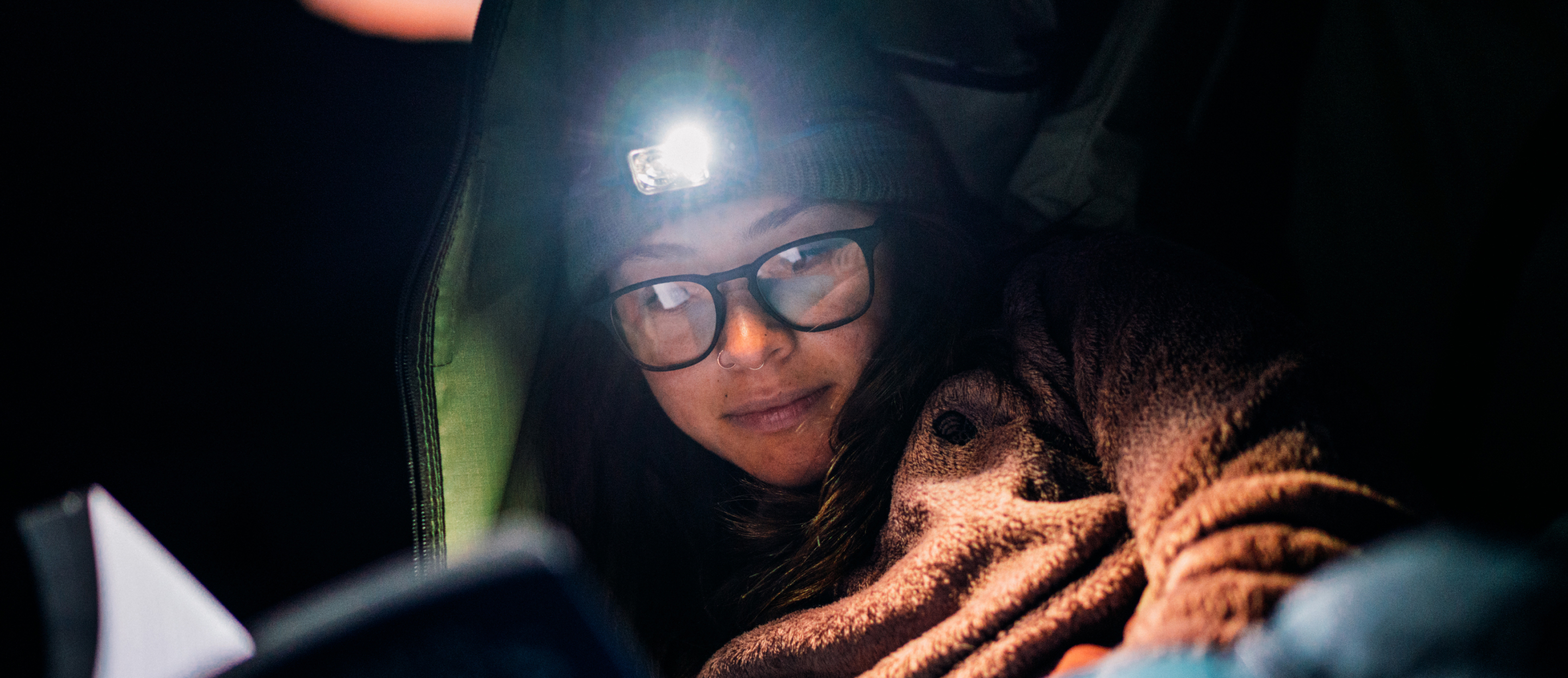 Woman reading with headlamp wearing Hunter 2.0 eyeglasses