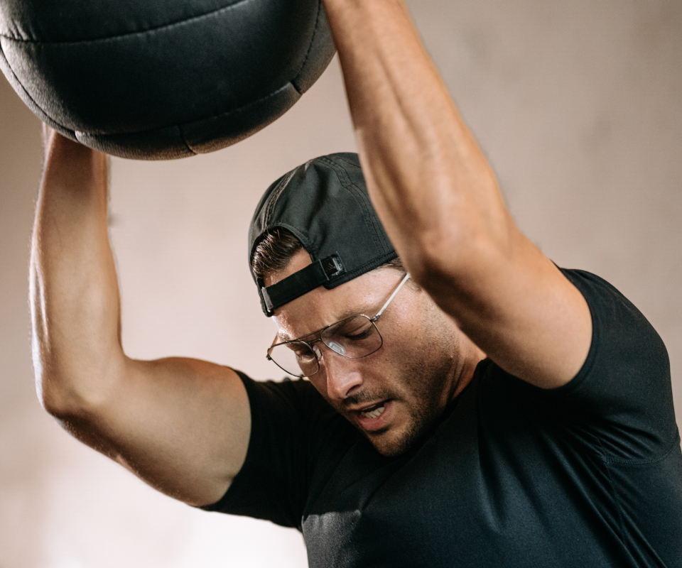 Man throwing medicine ball wearing Falcon eyeglasses