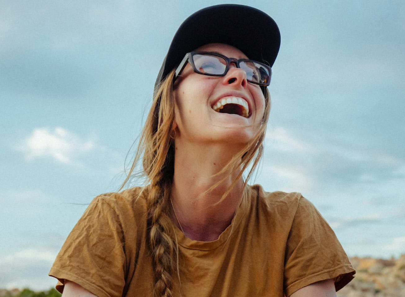 Woman laughing wearing black hat and mayfield eyeglasses