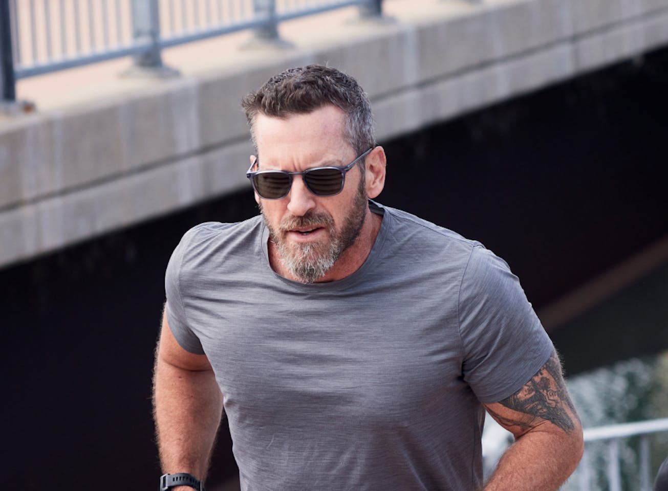 Man jogging on bridge wearing Cade sunglasses