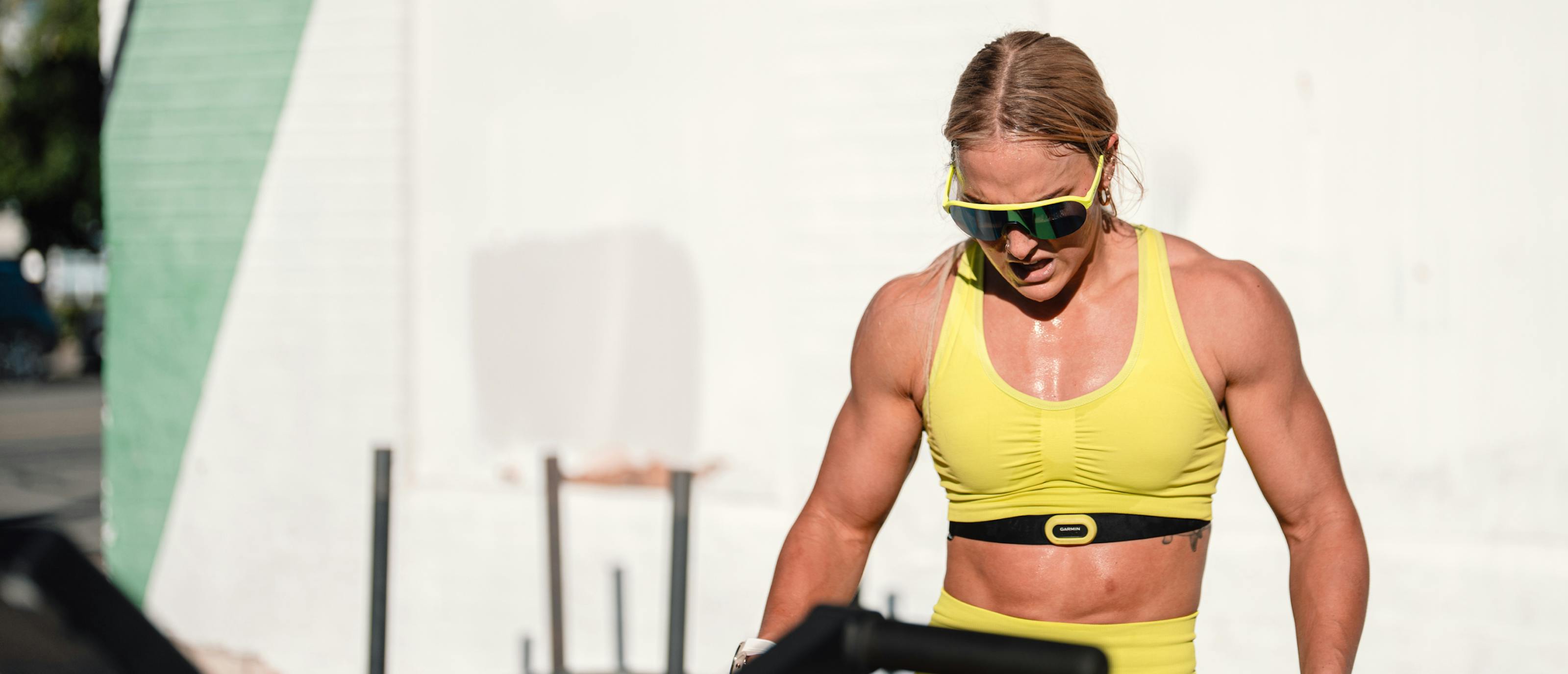 Woman working out in yellow top and ROKA sunglasses
