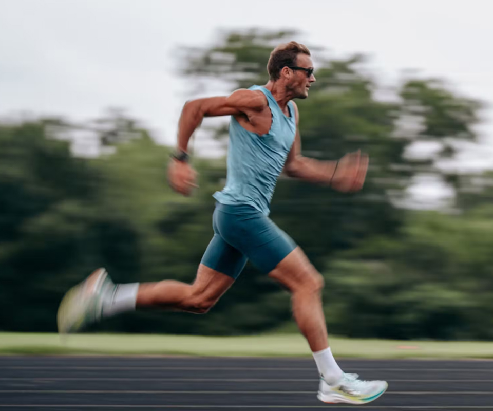 Man sprinting on track in blue shirt