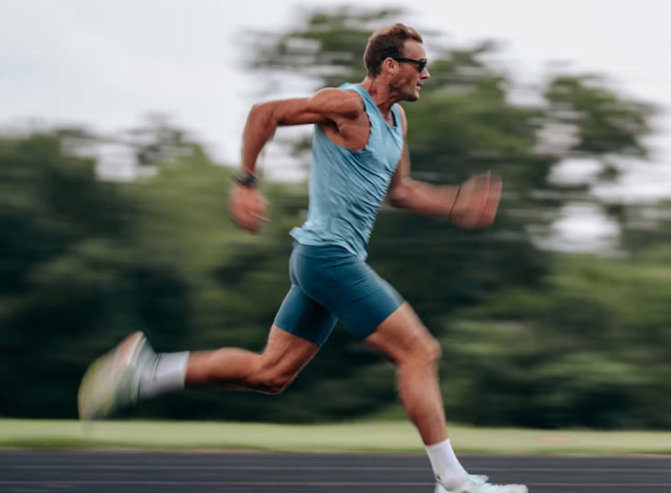 Man sprinting on track in blue shirt
