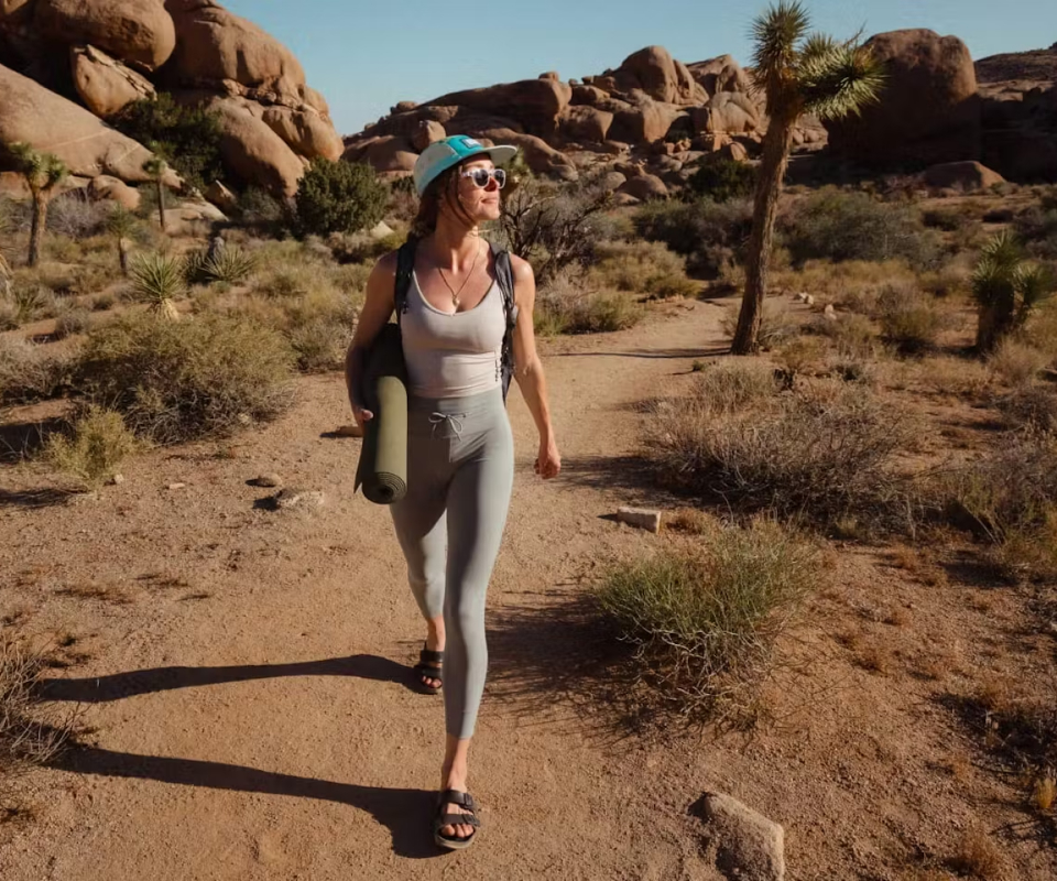 Woman walking in desert wearing blue hat and Hamilton sunglasses