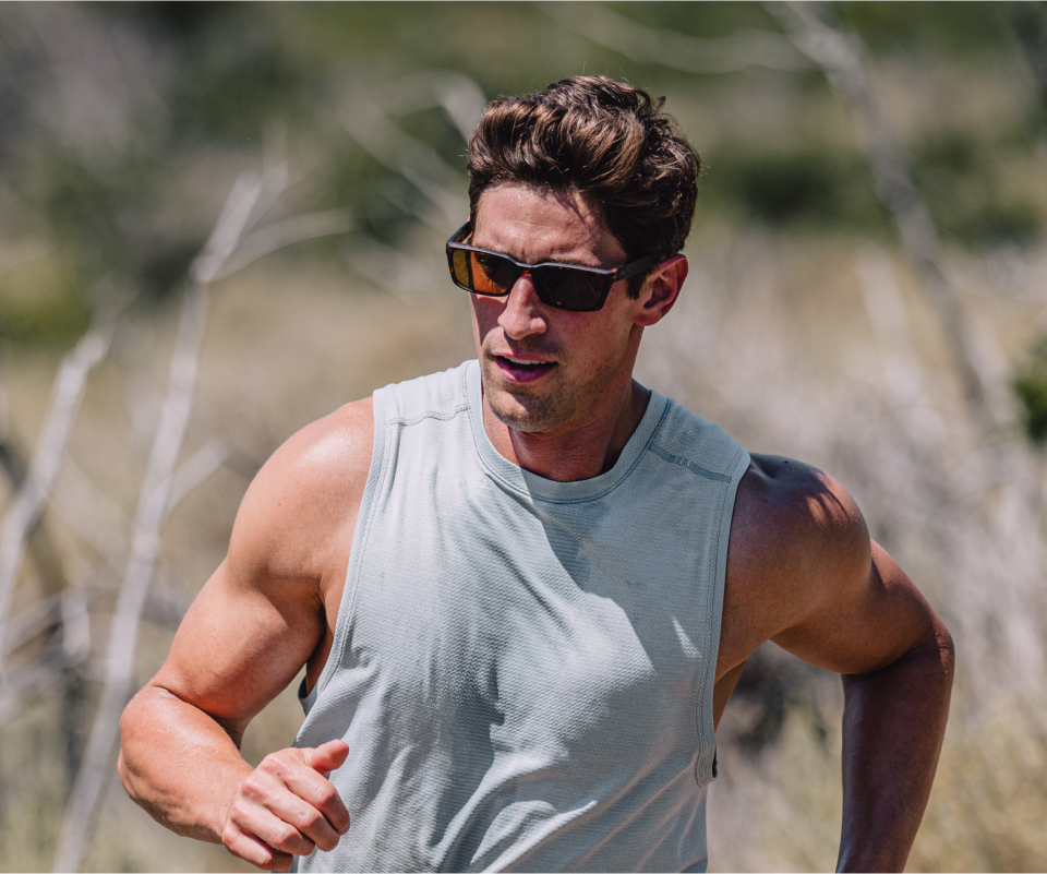 Man running in desert in tank top and Mayfield sunglasses