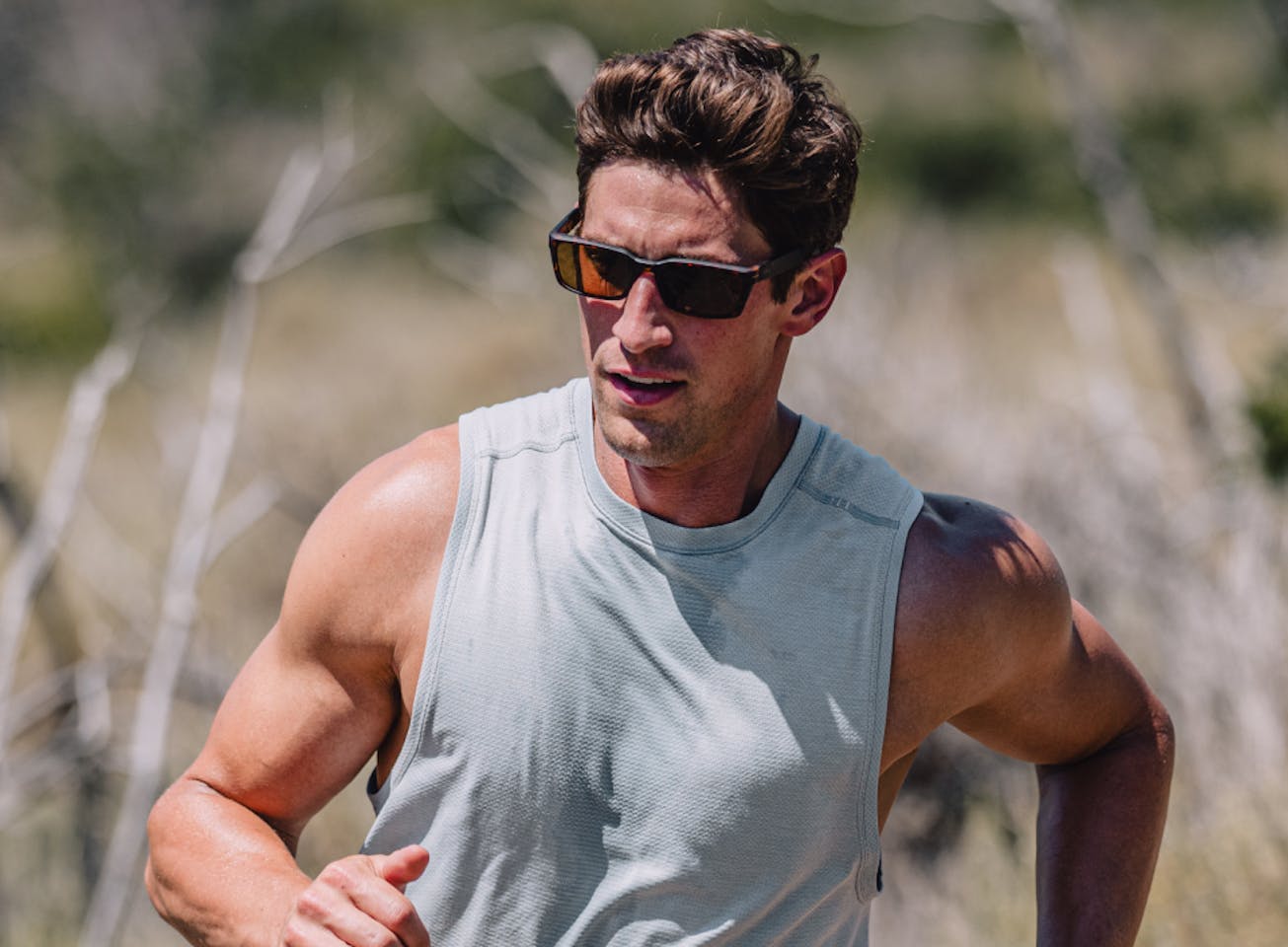 Man running in desert in tank top and Mayfield sunglasses