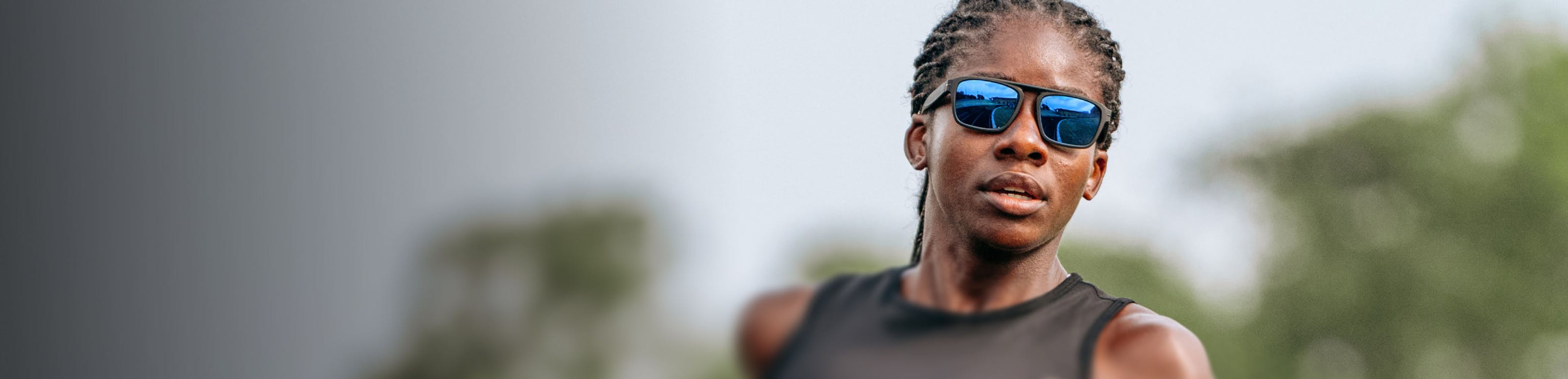 Woman wearing black tank top and blue mirrored ROKA sunglasses
