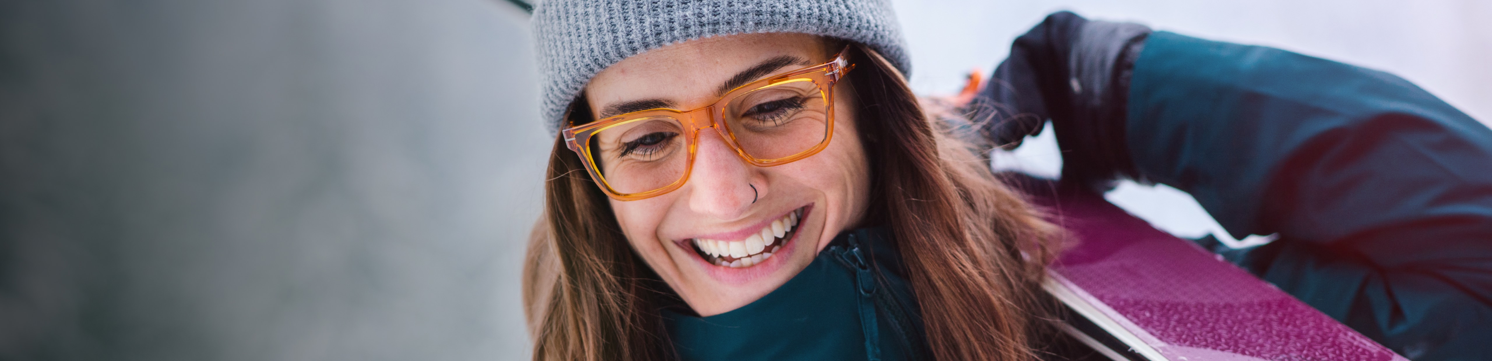 Woman smiling carrying skis and wearing Lockhart eyeglasses