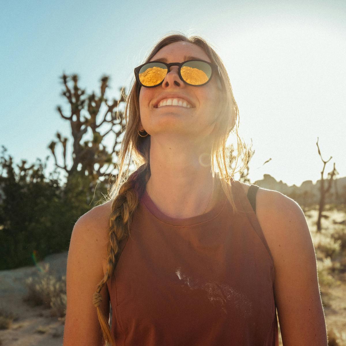 Woman smiling in desert wearing Oslo gold mirror sunglasses