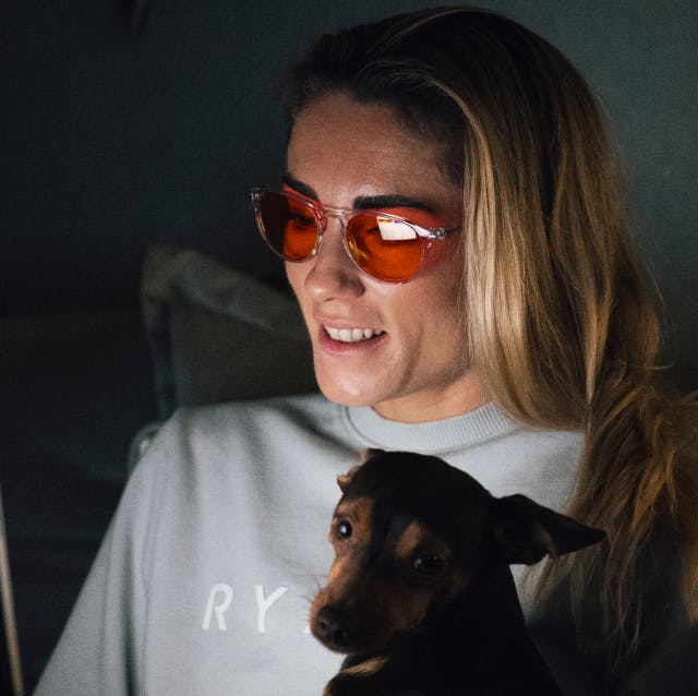 Woman working on her laptop holding dog wearing ROKA Wind Down glasses