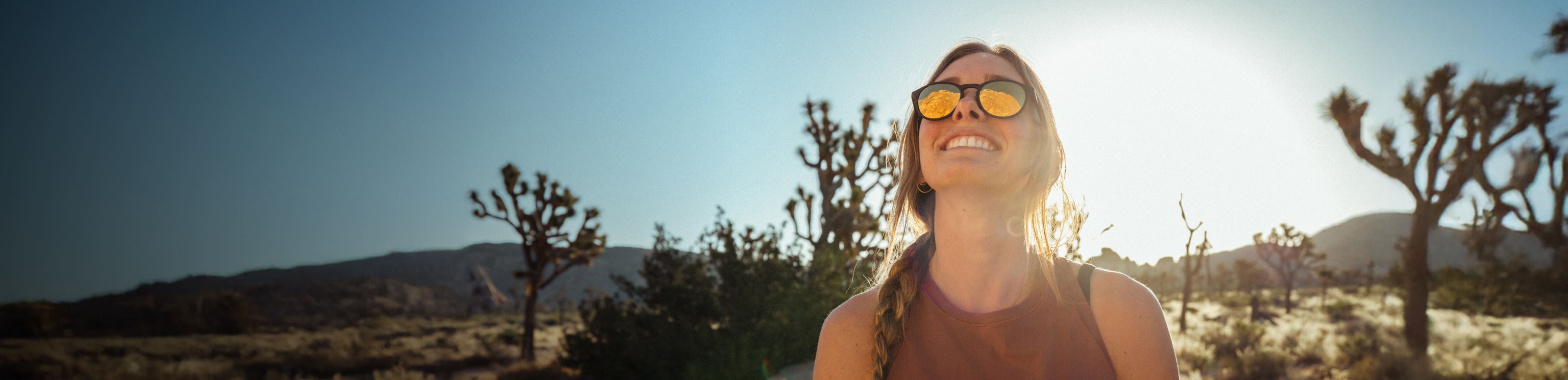 Woman smiling in desert wearing gold mirror ROKA sunglasses