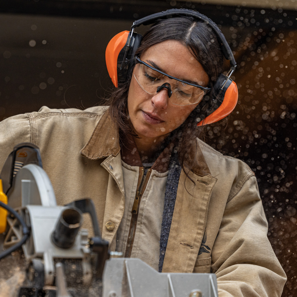Woman with chainsaw cutting wood wearing ROKAs