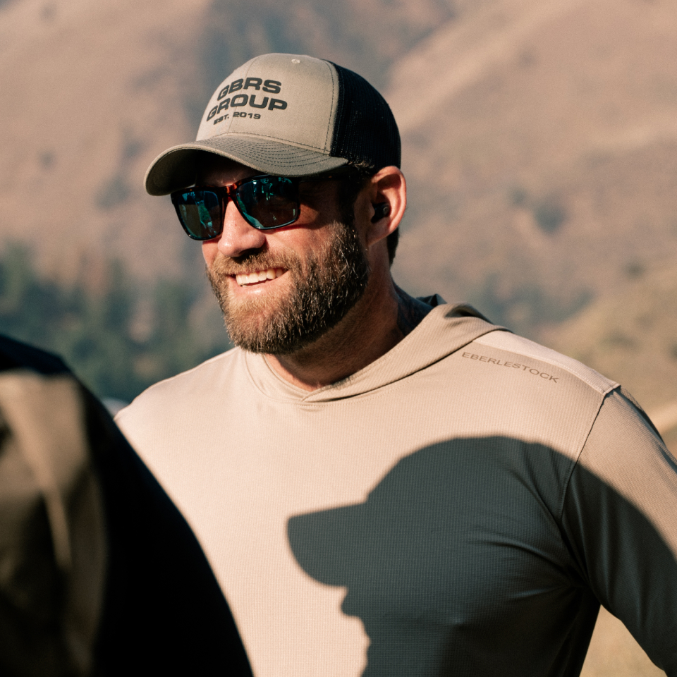 Man smiling wearing green hat and Tactical glasses