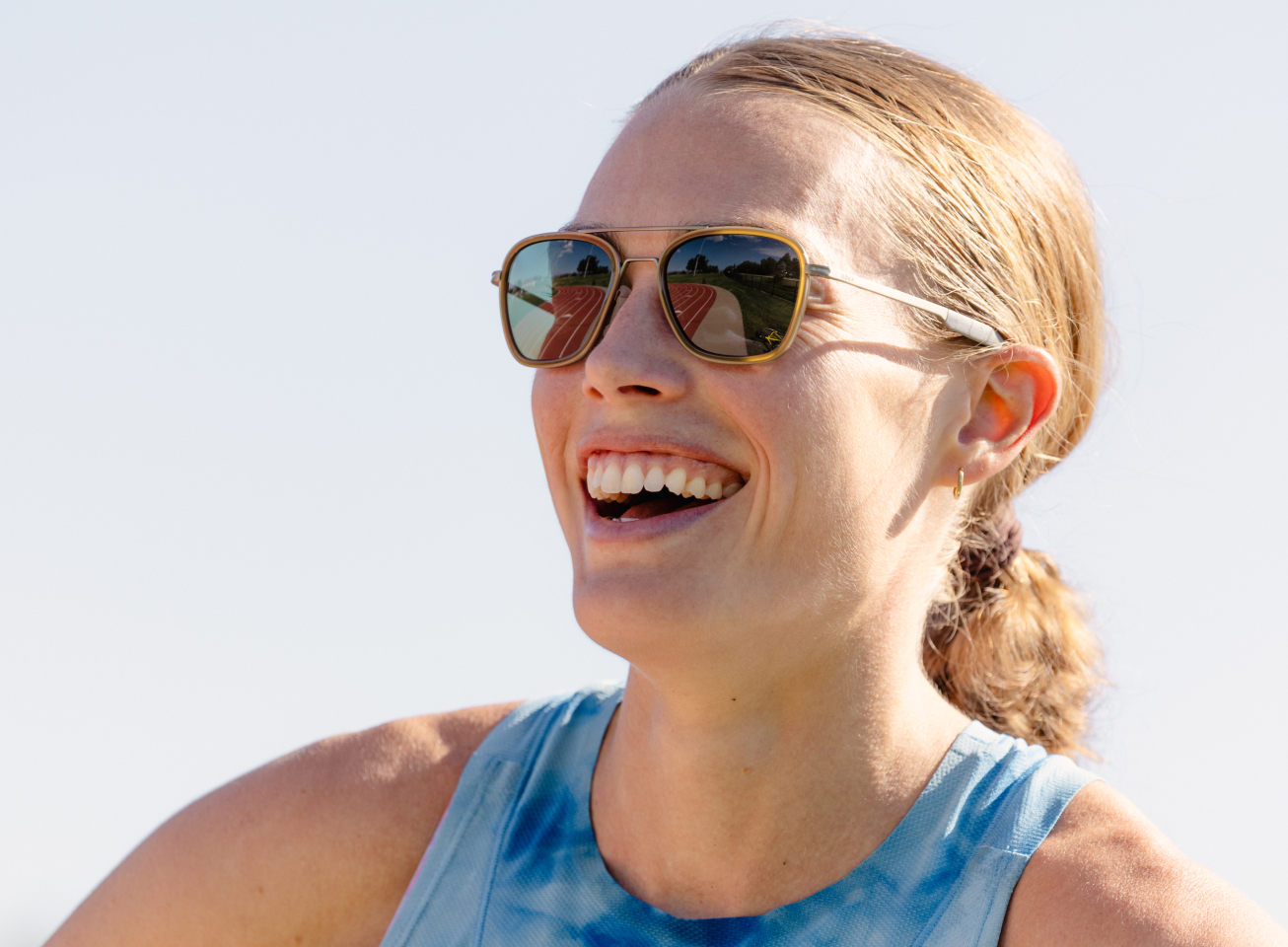 Woman smiling in blue tank top and Falcon Fusion sunglasses