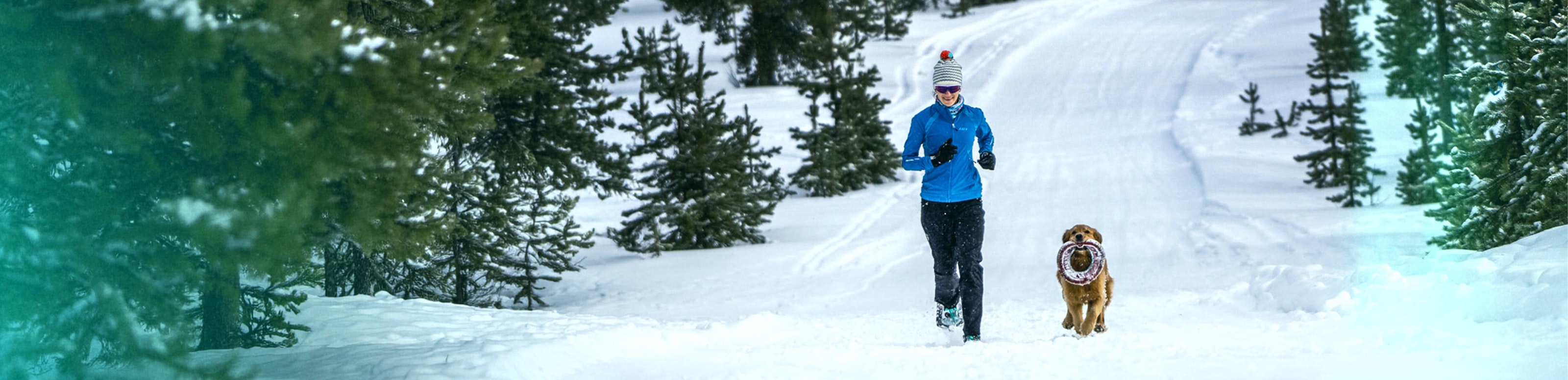 Woman jogging with god in snowy forest