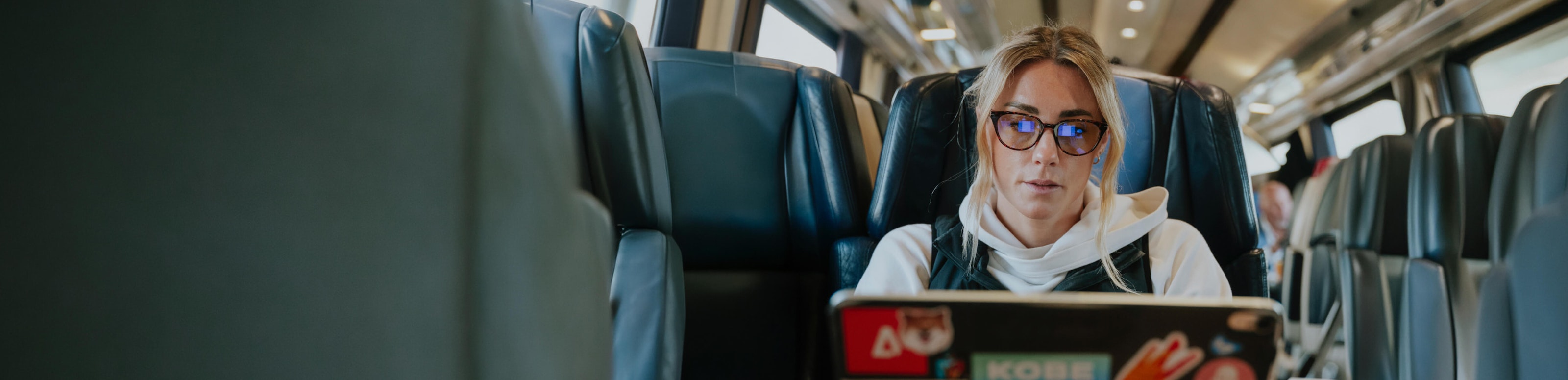 Woman on airplane using laptop and amber glasses