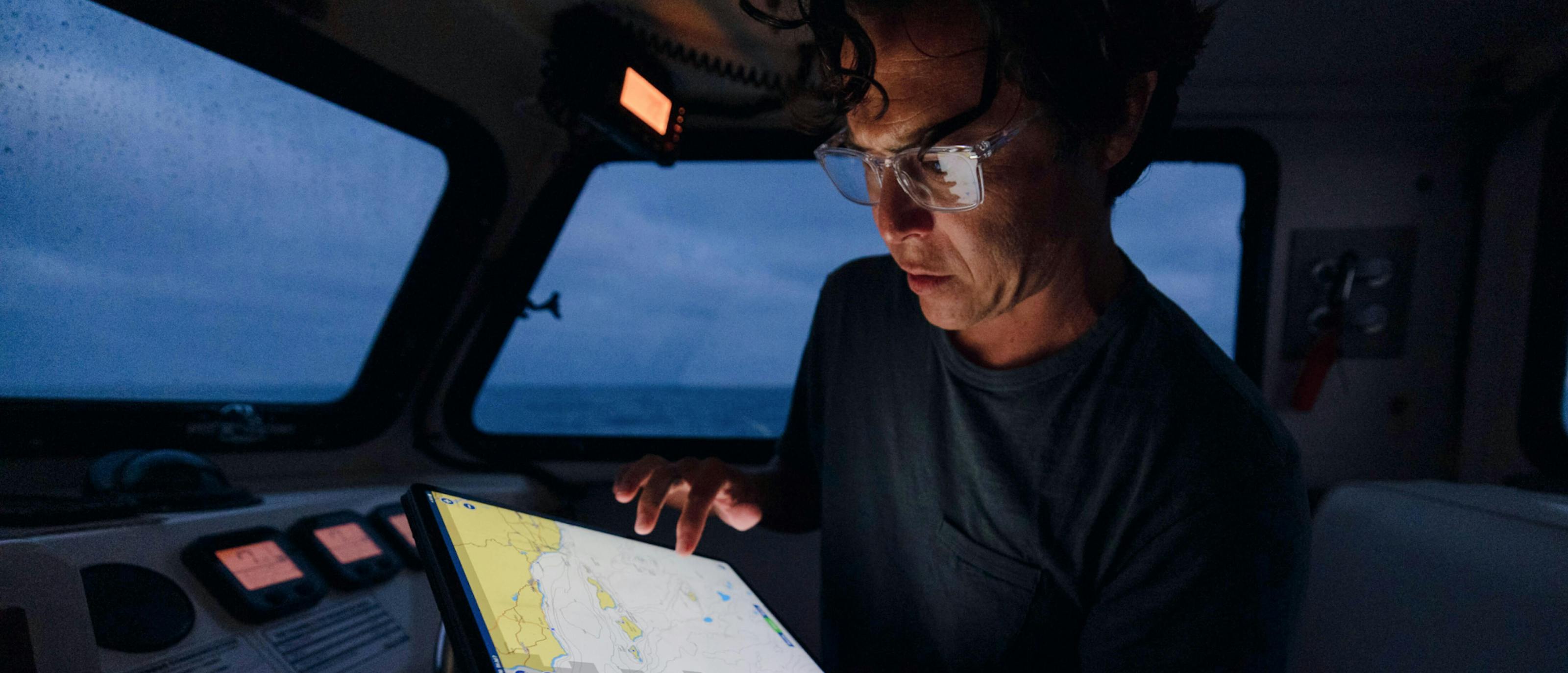 Man using tablet on boat wearing Palmer readers