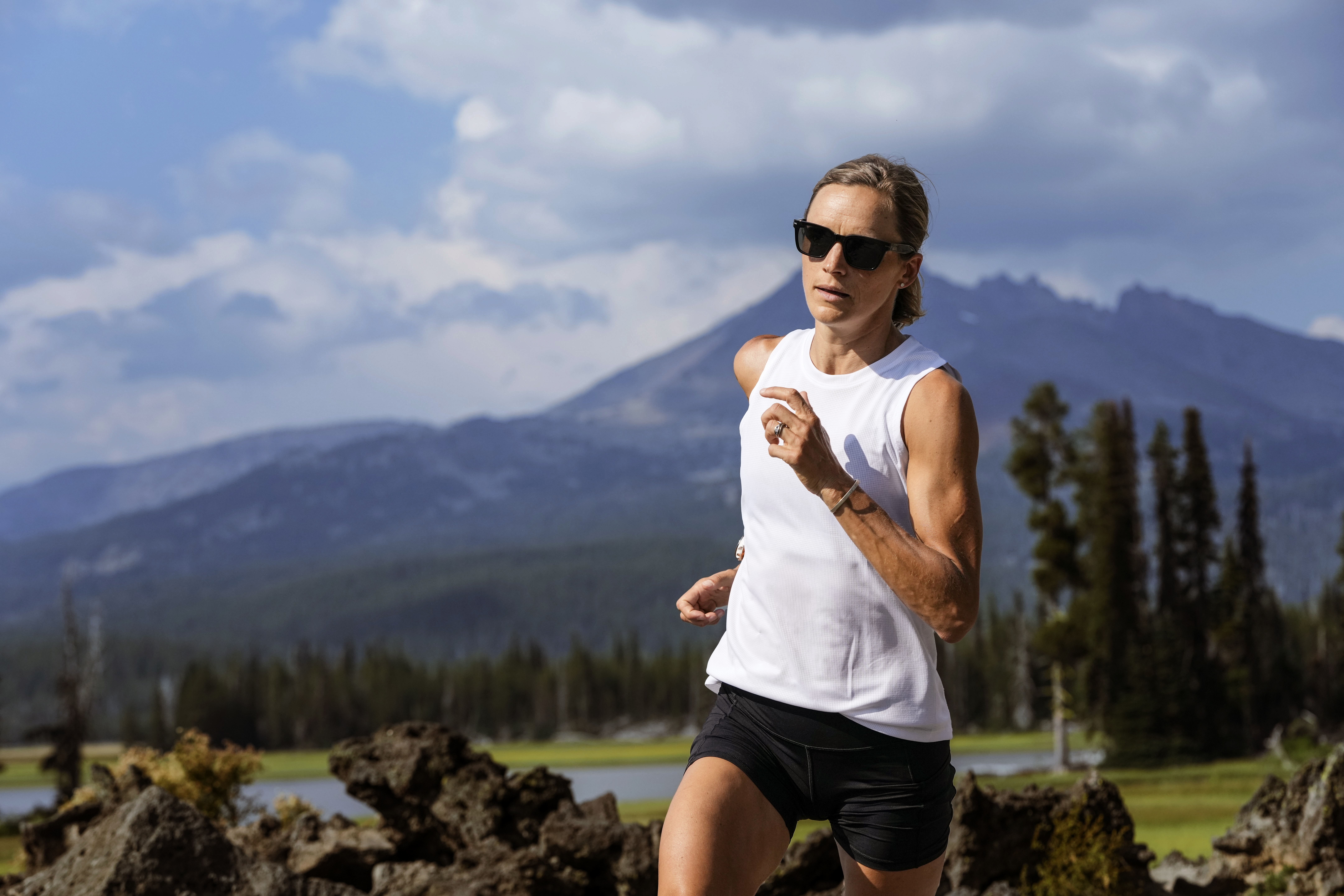 Woman jogging in white tank top in front of mountain