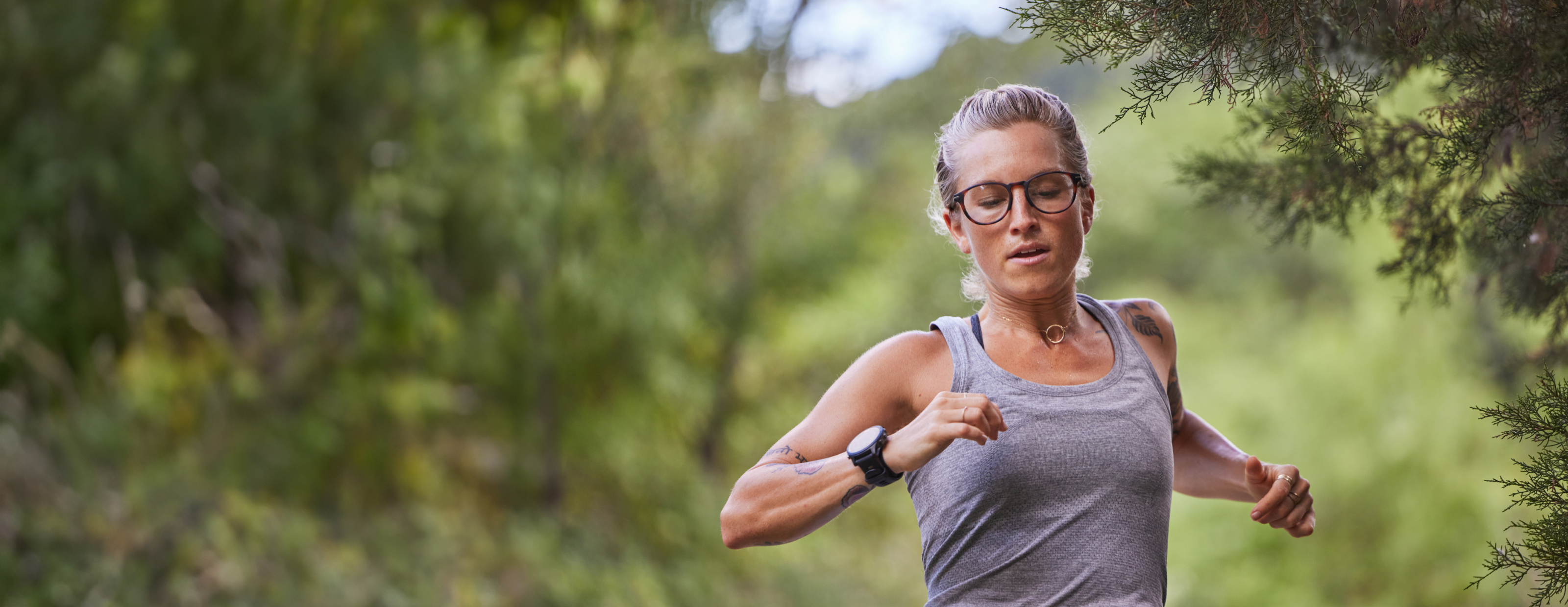 Woman running in woods wearing vest and ROKA eyeglasses