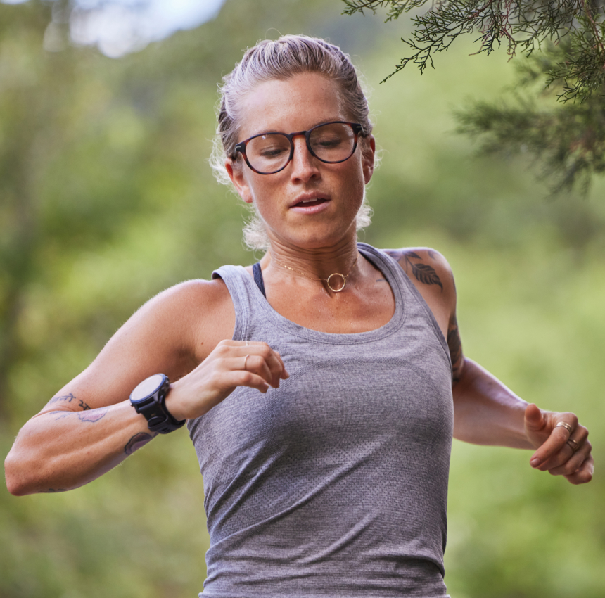Woman running in woods wearing vest and ROKA eyeglasses