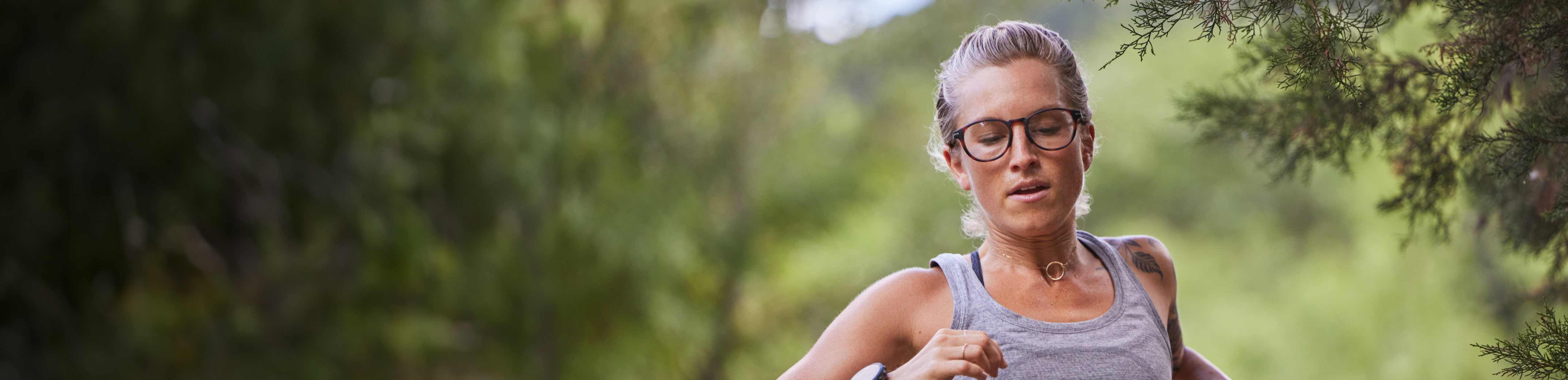Woman running in woods wearing vest and ROKA eyeglasses