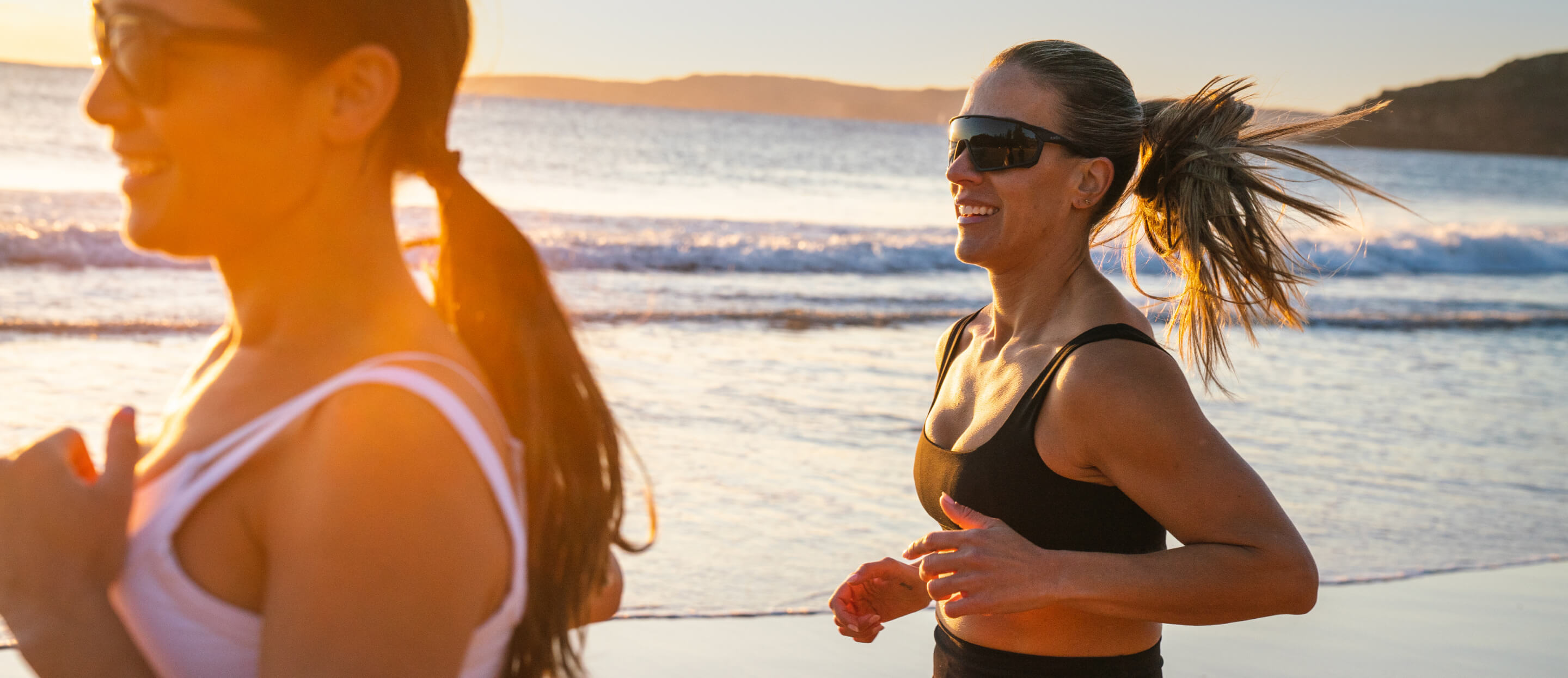 Women jogging on beach wearing ROKA sunglasses