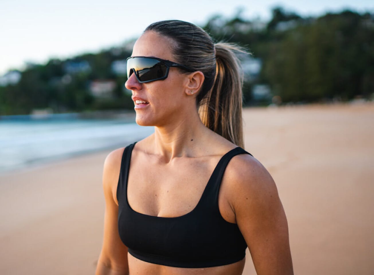Woman on beach wearing black tank top and ROKA sunglasses