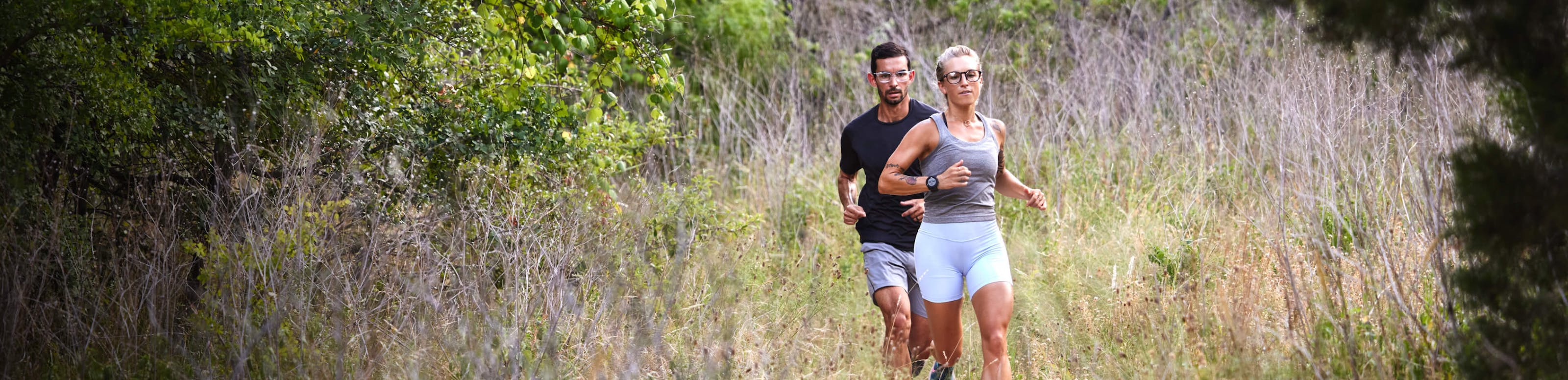 Man and woman running on brushy trail