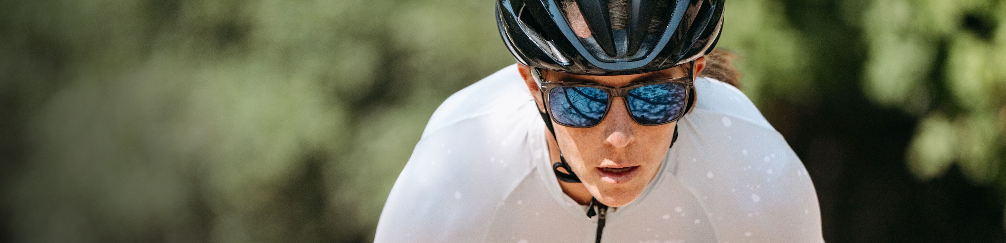 Woman cycling in white race suit and ROKA sunglasses