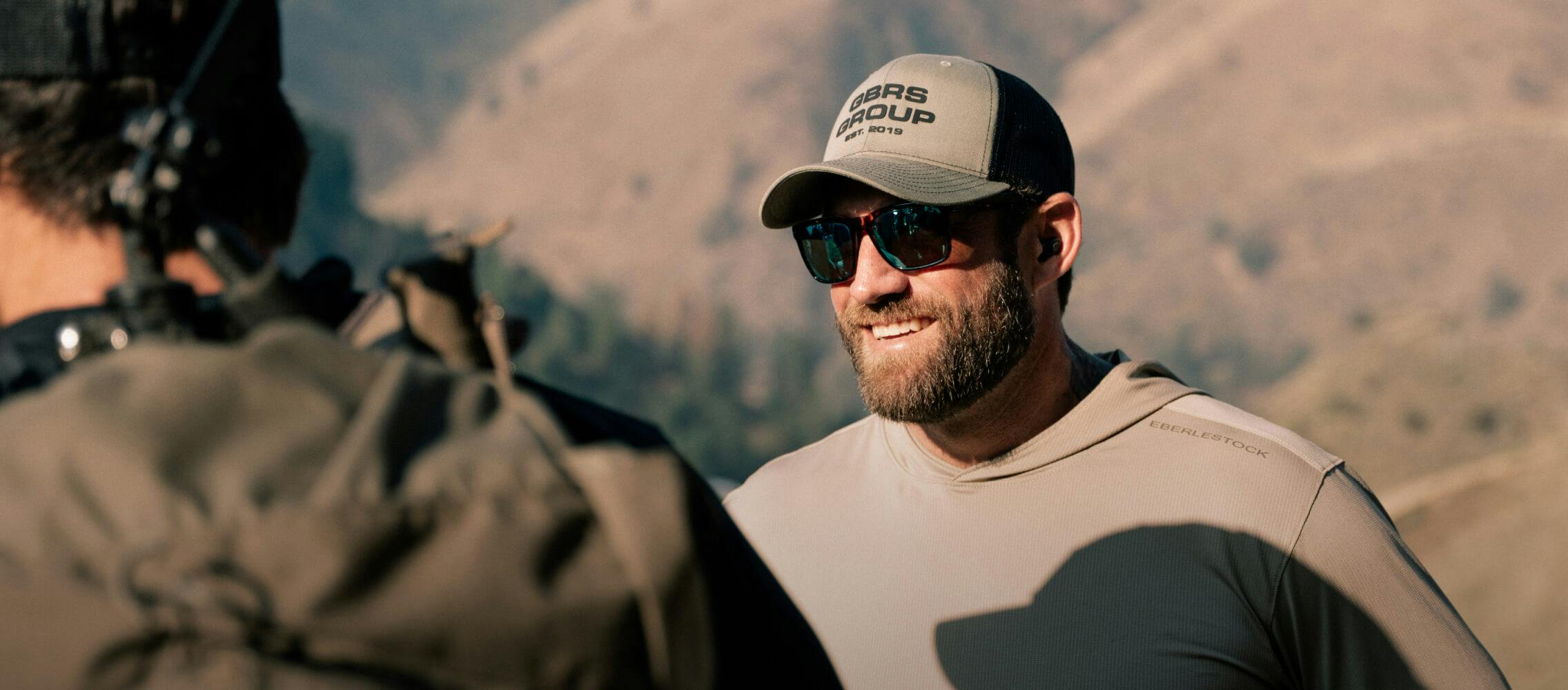 Man smiling wearing Barton sunglasses and tan hat