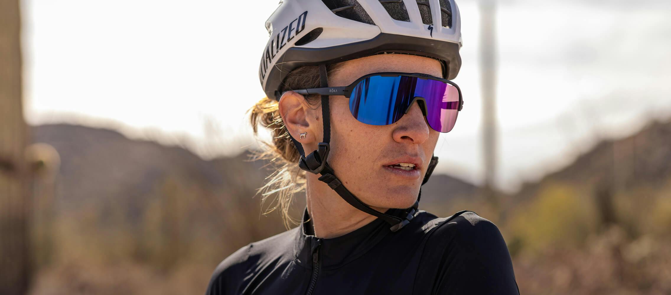 Woman wearing cycling helmet and purple shield ROKA sunglasses