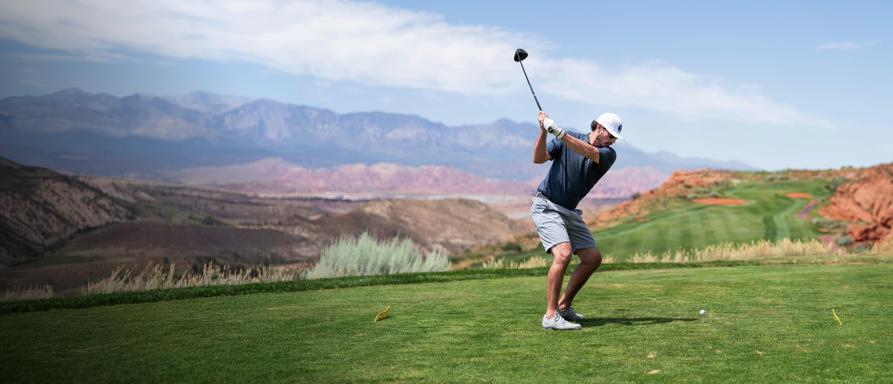 Man swinging golf club on desert golf course