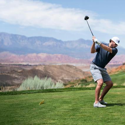 Man swinging golf club on desert golf course