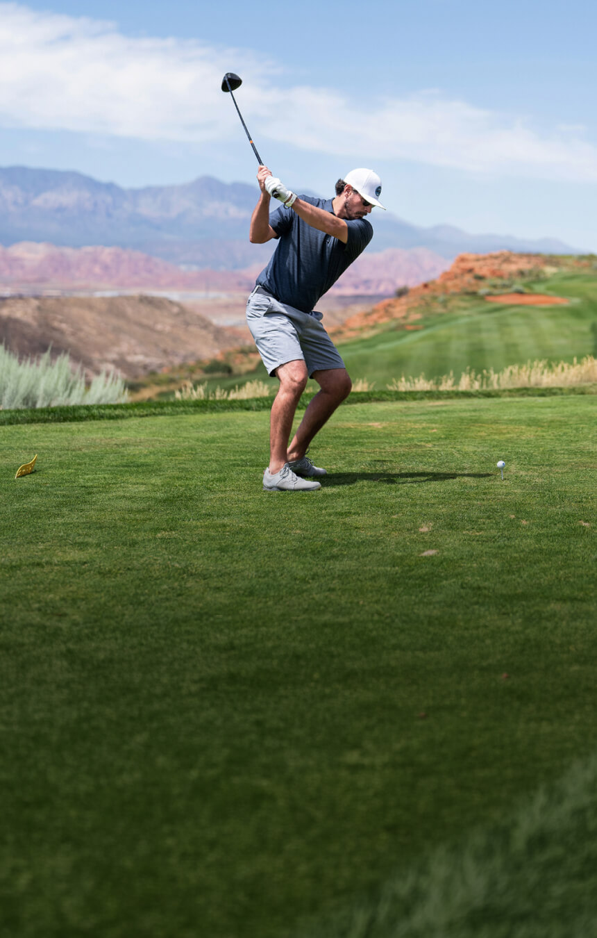Man swinging golf club on desert golf course