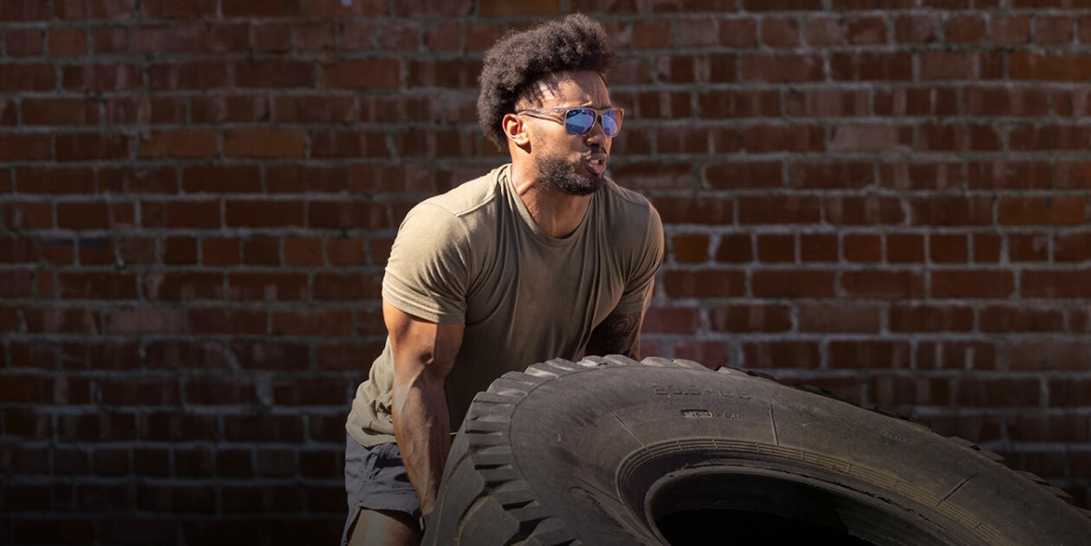 Man swinging flipping tire ROKA sunglasses