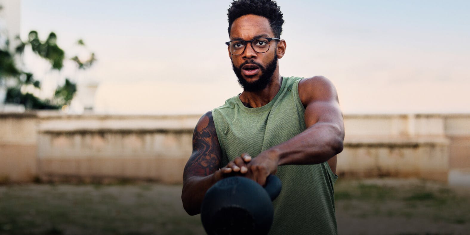 Man swinging kettle bell wearing ROKA eyeglasses