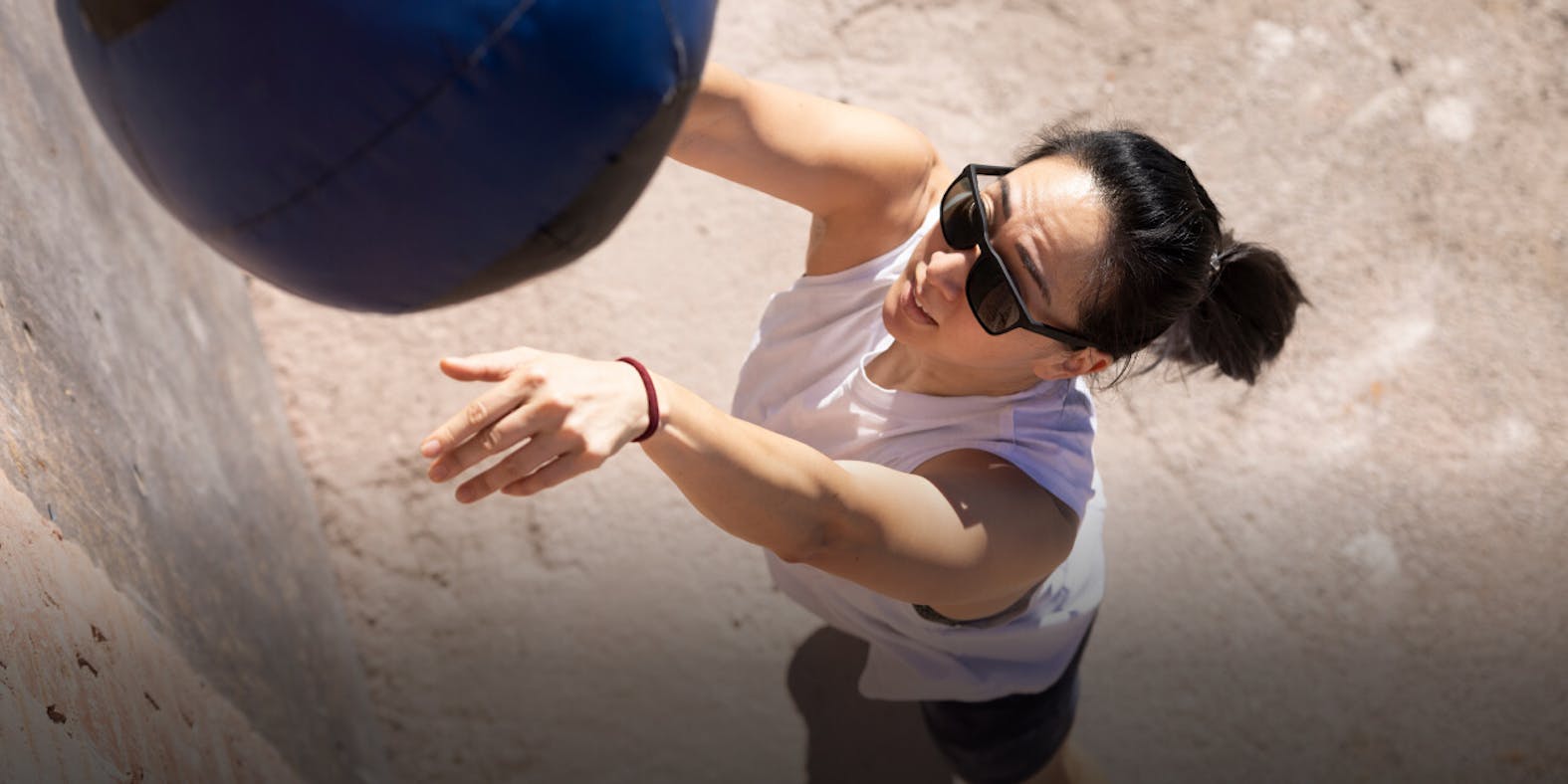 Woman working out with medicine ball wearing ROKA sunglasses
