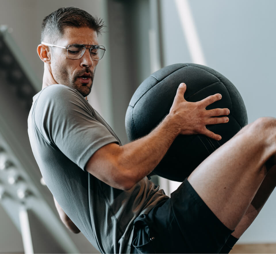 Man working out with medicine ball wearing ROKA eyeglasses