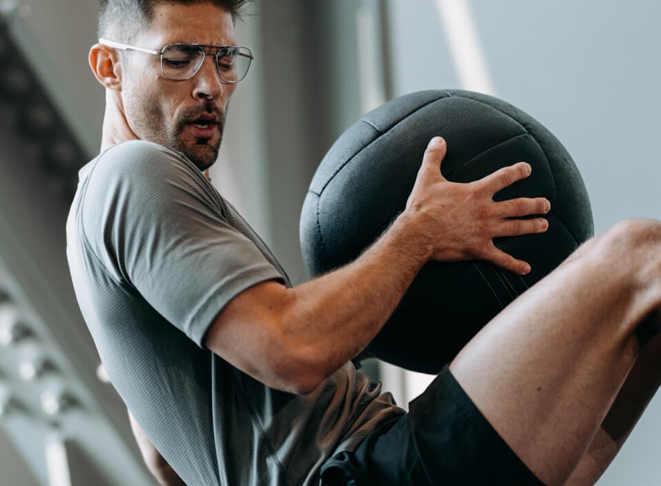 Man working out with medicine ball wearing ROKA eyeglasses